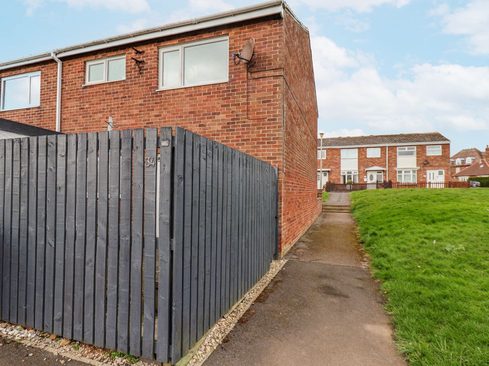 An outdoor view of a house with a fence and pathway at 34 Fountain Close Whitby