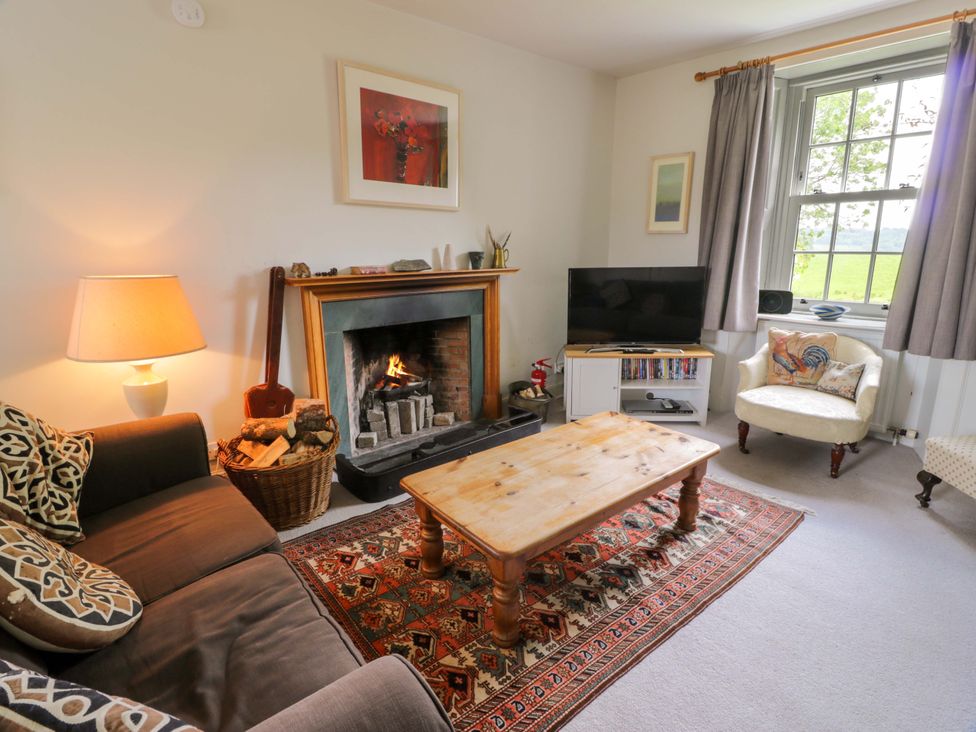 A living room with a fireplace and sofa at Townhead of Auchenbainzie near Thornhill