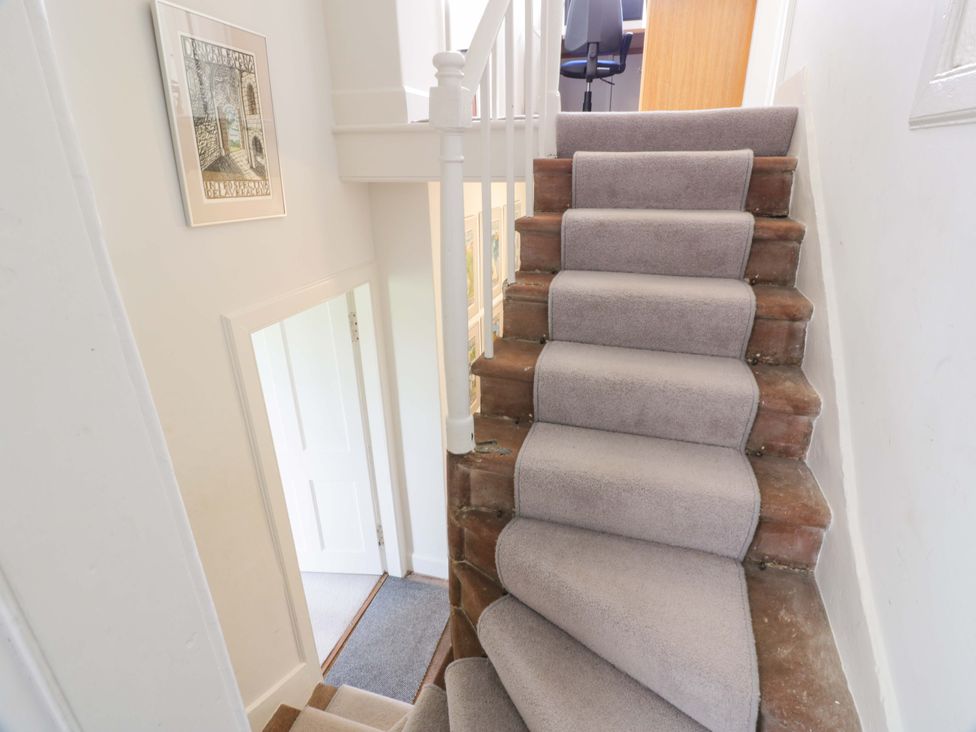 A staircase with a framed picture and a door at Townhead of Auchenbainzie near Thornhill