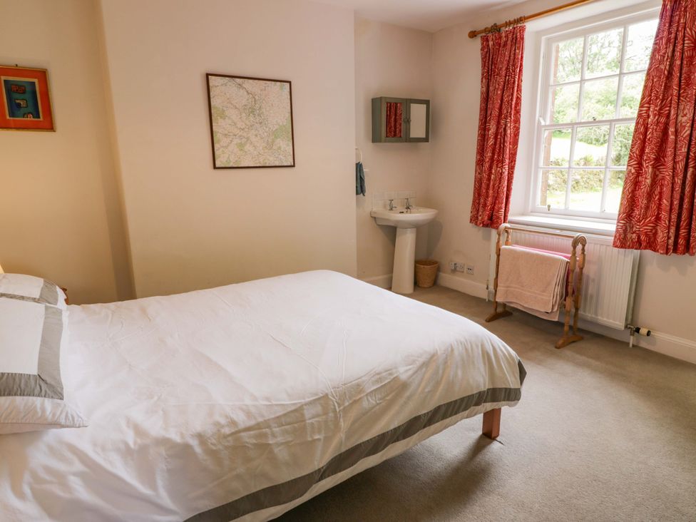 A bedroom with a bed, wash basin, and window at Townhead of Auchenbainzie near Thornhill