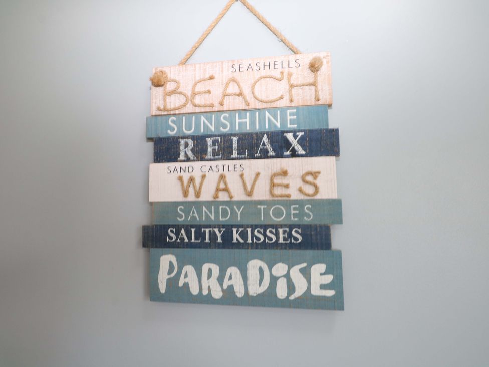 A wooden sign with various beach-themed words at Dymchurch Bungalow in Romney Marsh