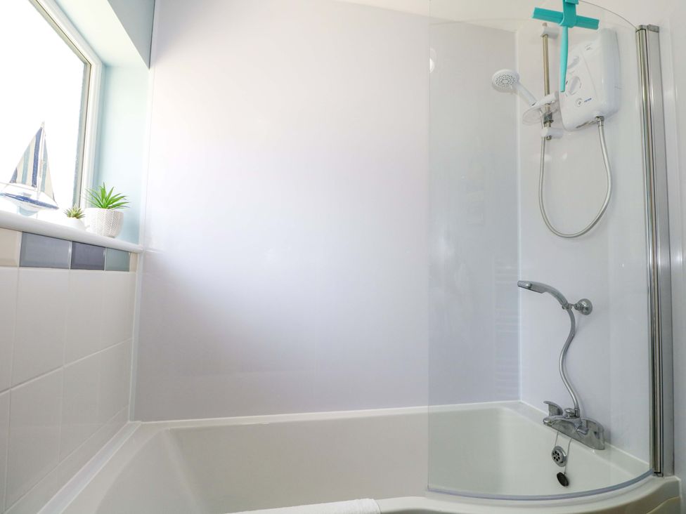 A bathroom with a shower over a bathtub and a window at Dymchurch Bungalow in Romney Marsh