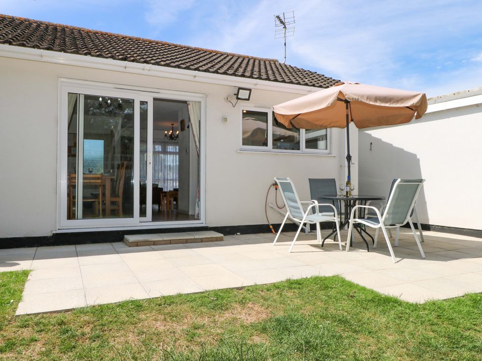 A garden with a table and chairs under an umbrella at Dymchurch Bungalow Romney Marsh