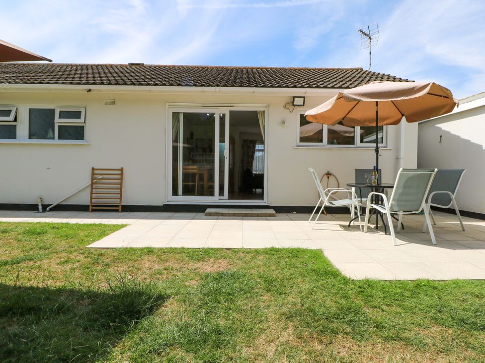 A garden with a patio area featuring a table and chairs at Dymchurch Bungalow in Romney Marsh