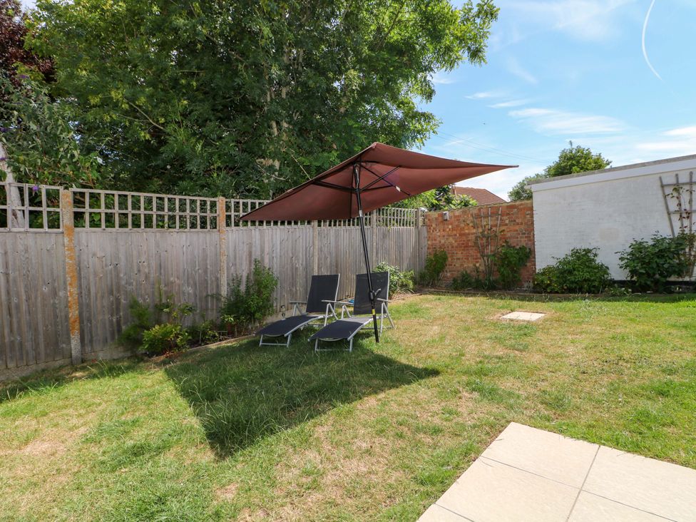 A garden with lounge chairs and an umbrella at Dymchurch Bungalow in Romney Marsh