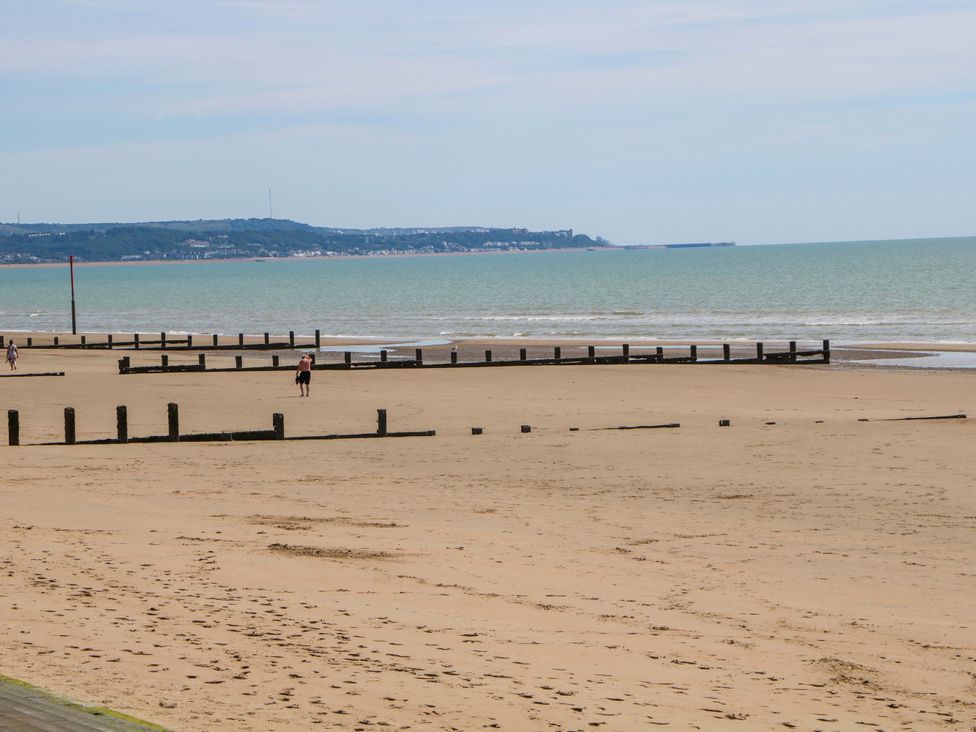 A beach with wooden posts and water at Dymchurch Bungalow in Romney Marsh