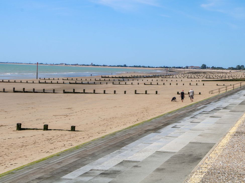A beach with people walking along the shore at Dymchurch Bungalow in Romney Marsh