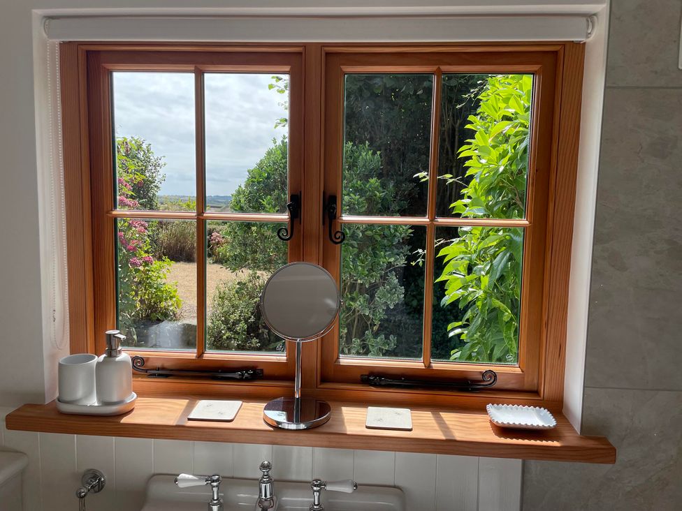 A bathroom with a window and a mirror at Bell Buoy Cottage in Morwenstow