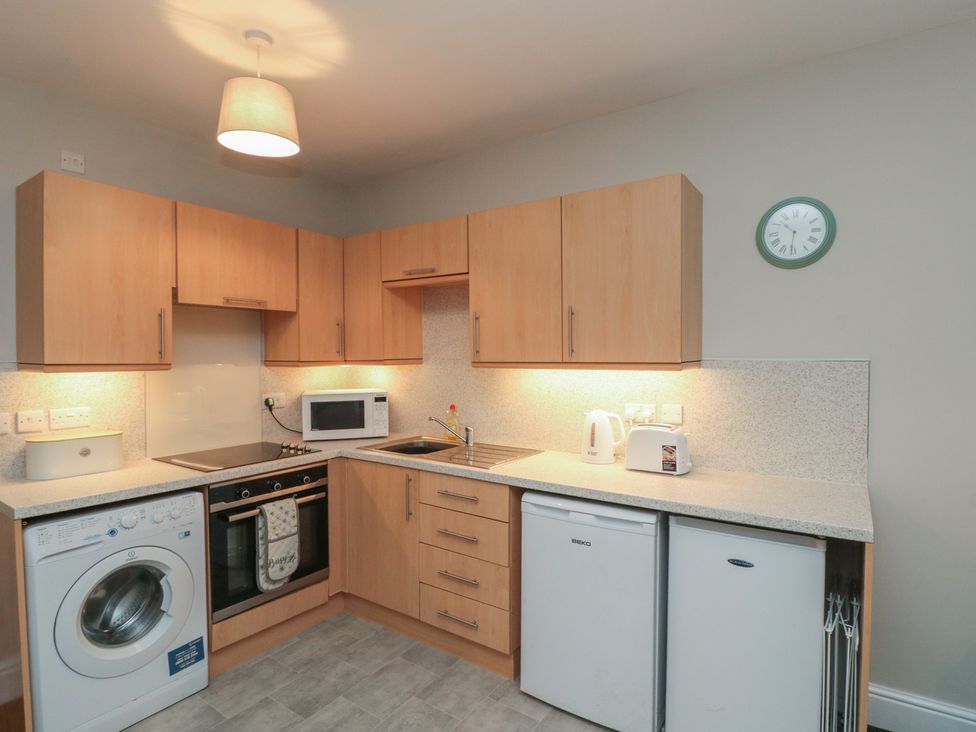 A kitchen with appliances including a washing machine, oven, and microwave at Beck View