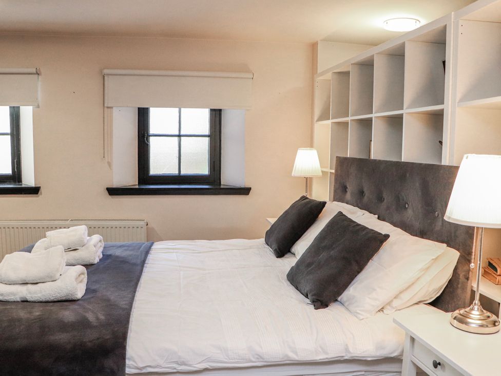 A bedroom with a bed and two windows at Mary Ann Apartment in Inverness