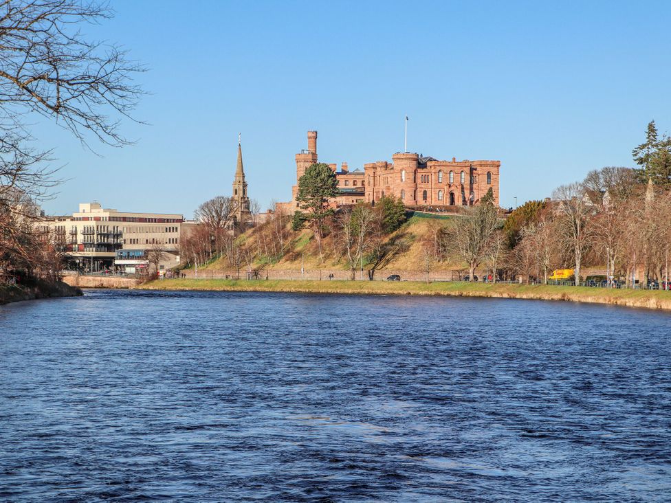 A river with a castle and buildings on the bank at Mary Ann Apartment in Inverness