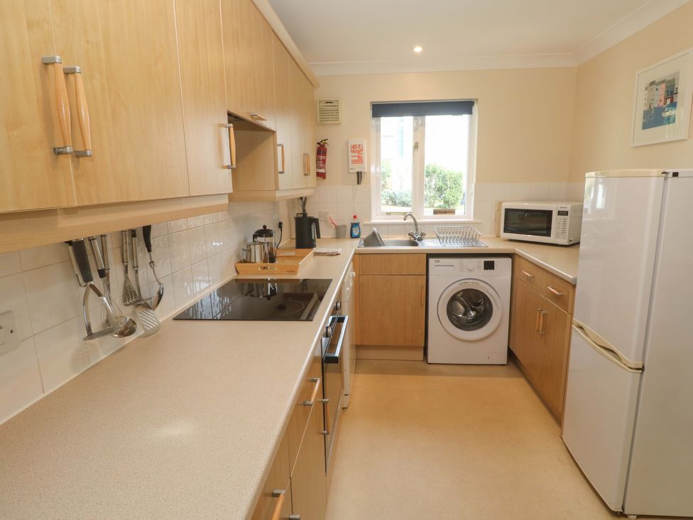 A kitchen with cabinets, sink, stove, washing machine, and refrigerator at Pheasants Walk in Falmouth