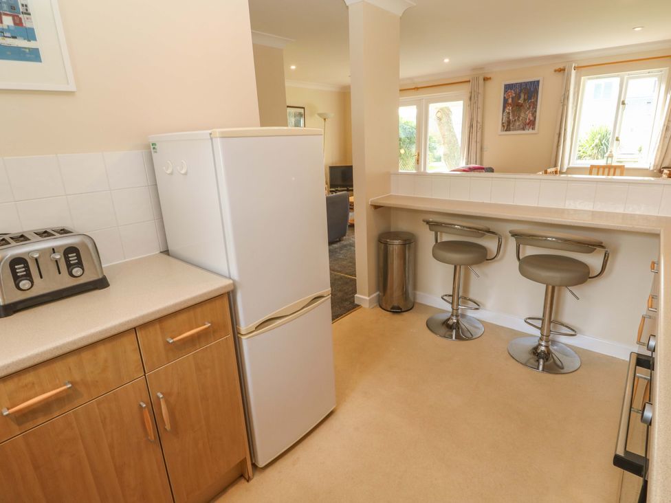 A kitchen with a refrigerator and bar stools at Pheasants Walk Falmouth