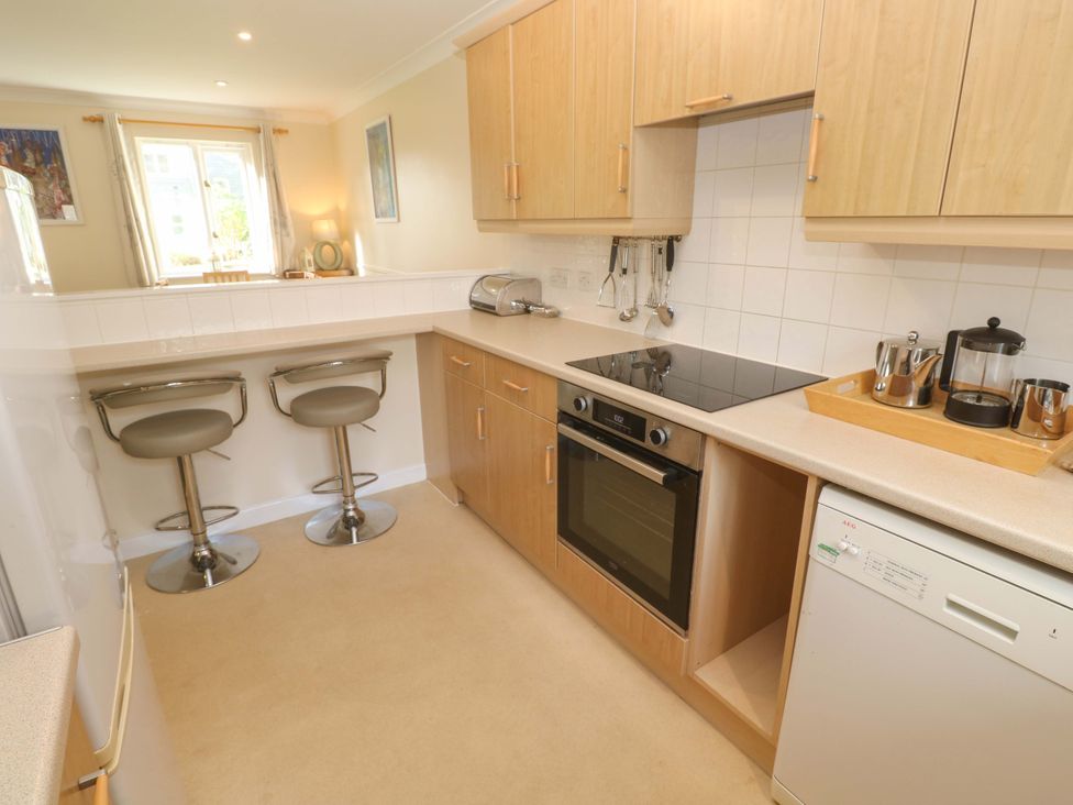A kitchen with appliances and bar stools at Pheasants Walk in Falmouth