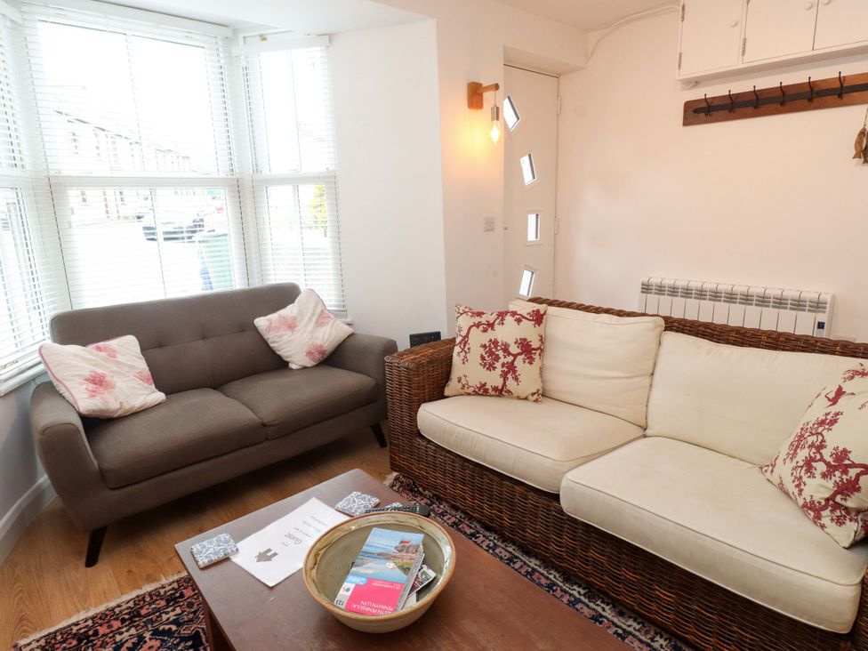A living room with a sofa, armchair, and table at Bodefi in Nefyn