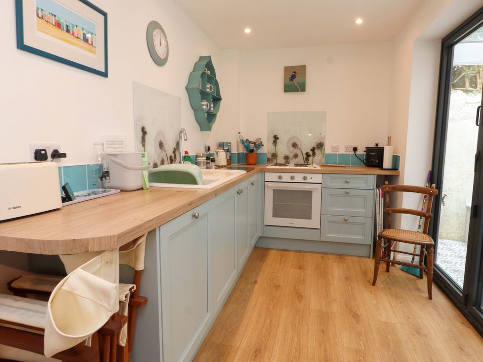 A kitchen with cabinets, a sink, and a clock at Bodefi in Nefyn