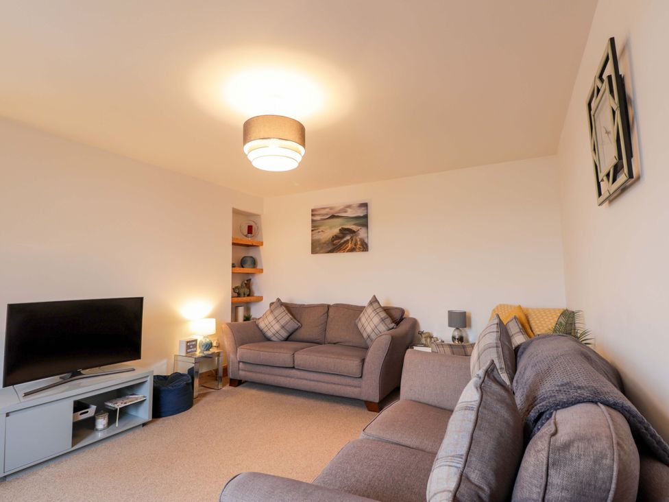 A living room with sofas and a television at Nanville in Muir of Ord and Beauly