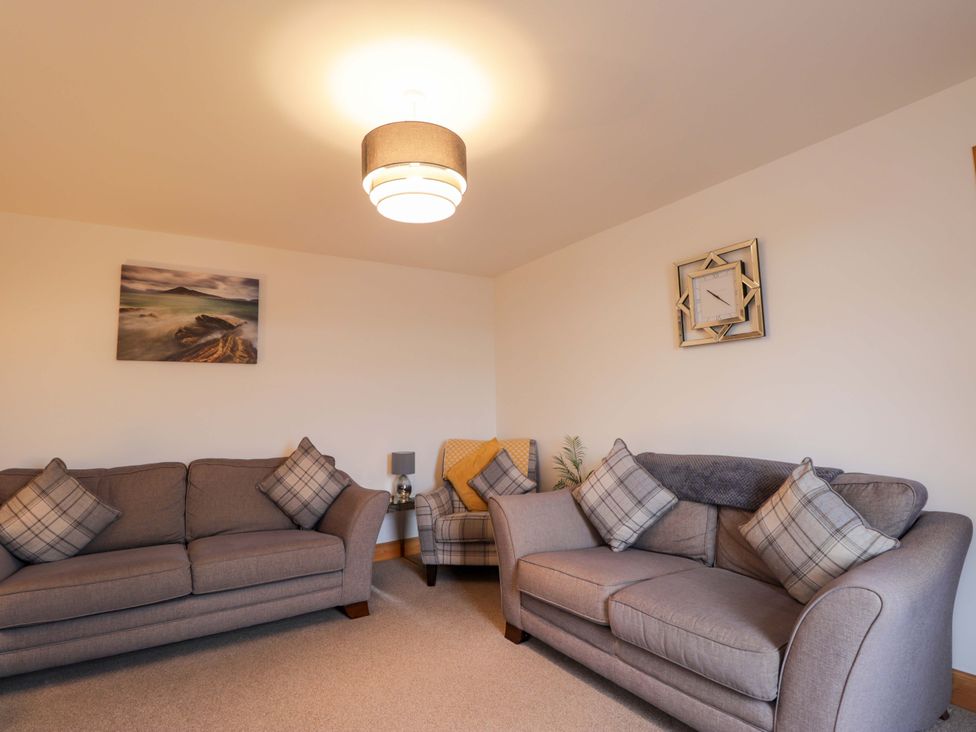 A living room with sofas and a lamp at Nanville in Muir of Ord and Beauly