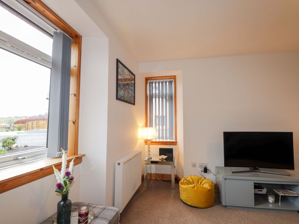 A living room with a tv and a side table at Nanville in Muir of Ord and Beauly