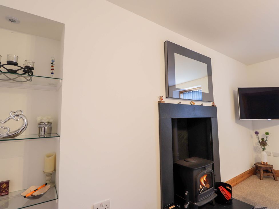 A living room with a wood stove and a television at Nanville in Muir of Ord and Beauly