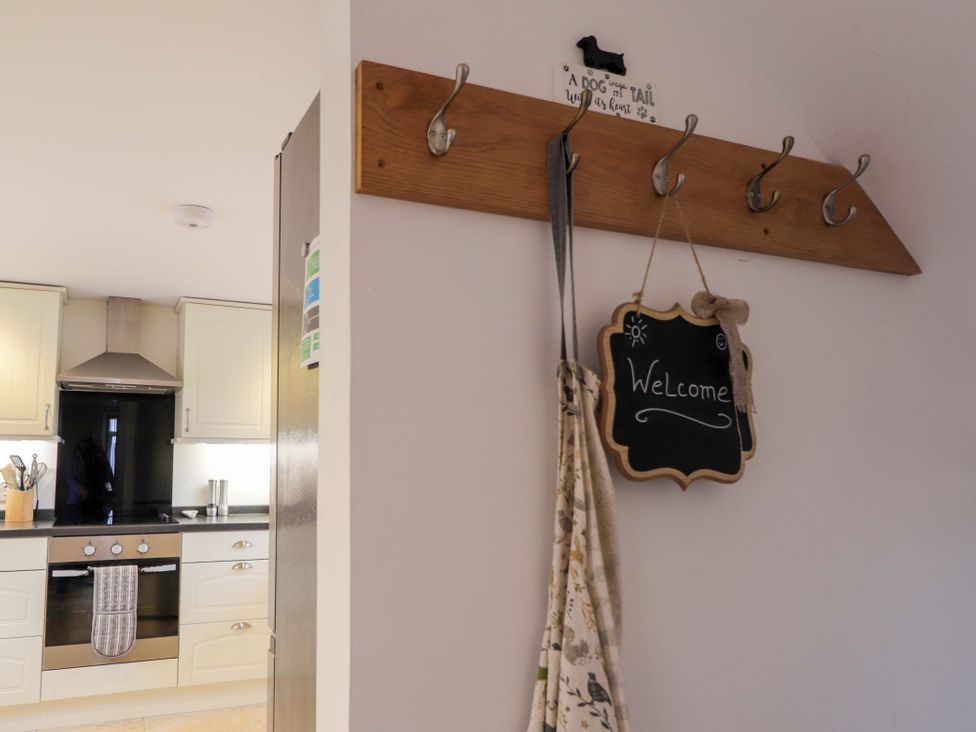 A coat rack and welcome sign in a kitchen at Nanville in Muir of Ord and Beauly