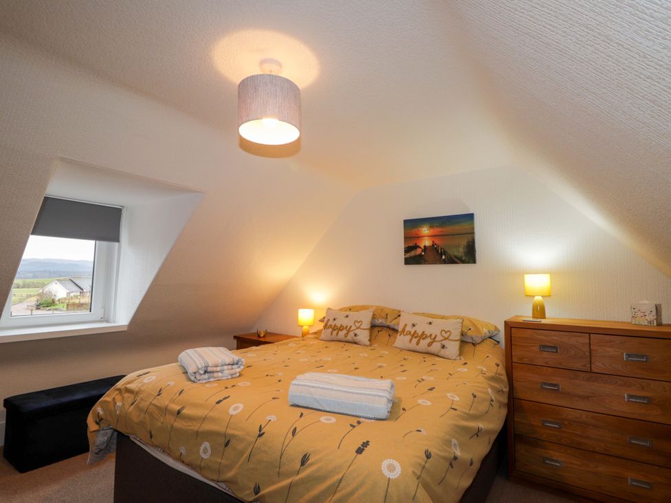 A bedroom with a bed, bedside lamps and a window at Nanville in Muir of Ord and Beauly