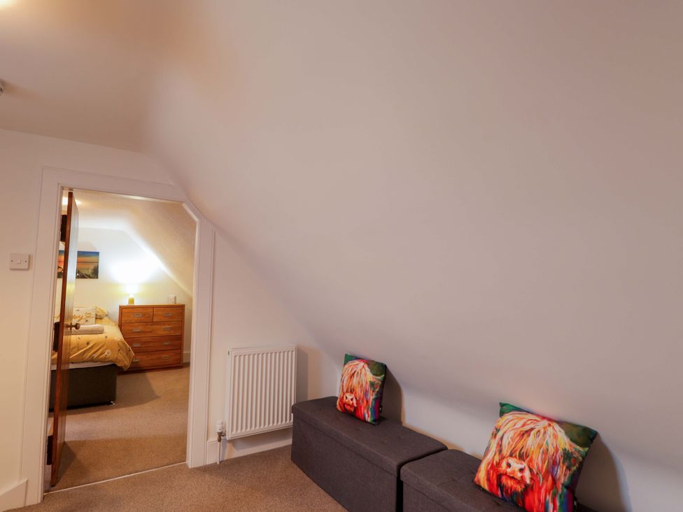 A bedroom with a dresser and sofa at Nanville in Muir of Ord and Beauly