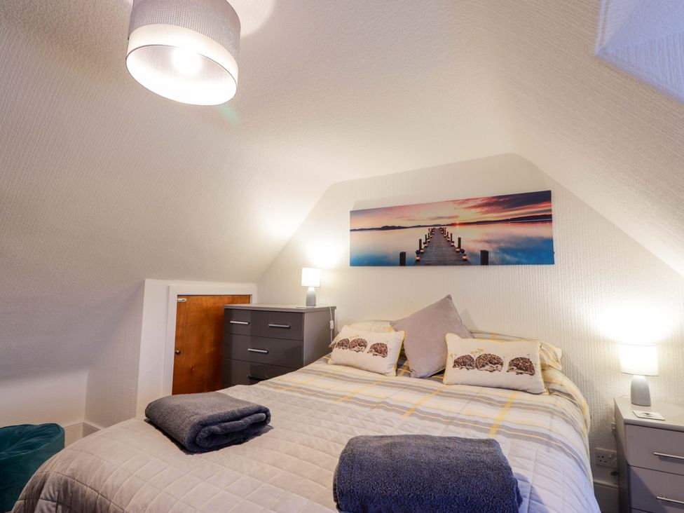 A bedroom with a bed and nightstand at Nanville in Muir of Ord and Beauly