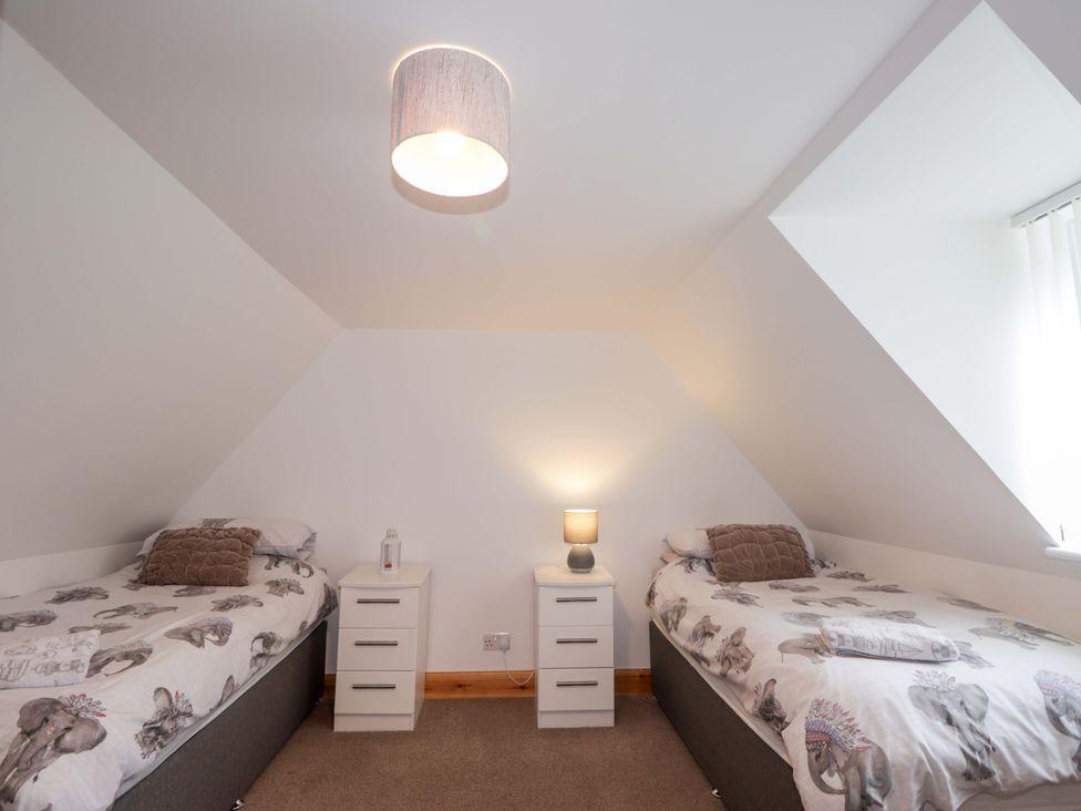 A bedroom with two beds and bedside tables at Nanville in Muir of Ord and Beauly