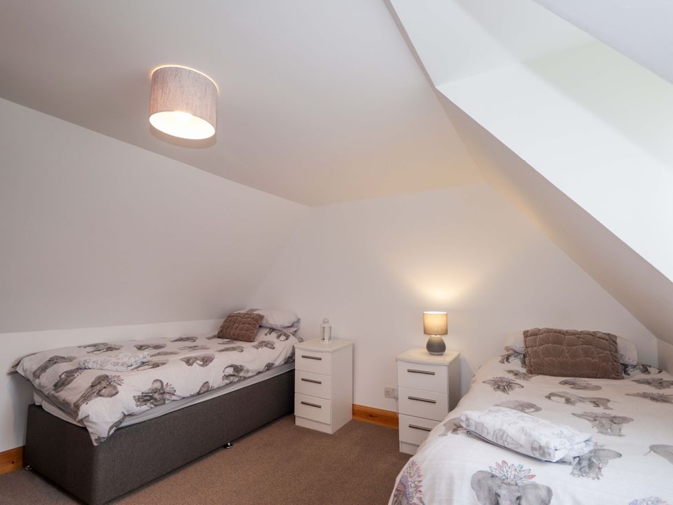 A bedroom with two beds and nightstands at Nanville in Muir of Ord and Beauly