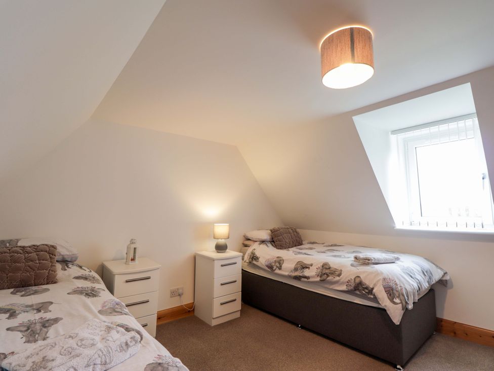 A bedroom with two beds and a window at Nanville Muir of Ord and Beauly