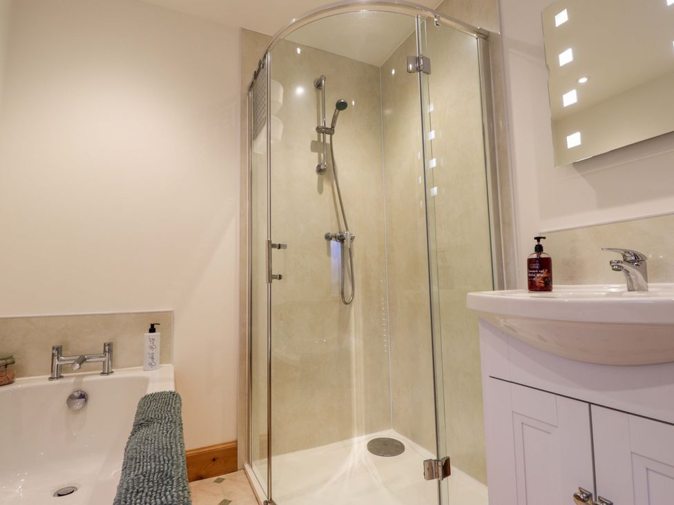 A bathroom with a shower, bathtub, and sink at Nanville in Muir of Ord and Beauly