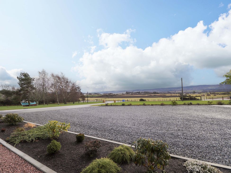 An outdoor area with a gravel driveway and trees at Nanville Muir of Ord and Beauly
