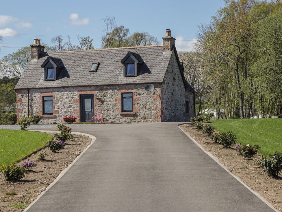 A house with a driveway and flower beds at Nanville in Muir of Ord and Beauly