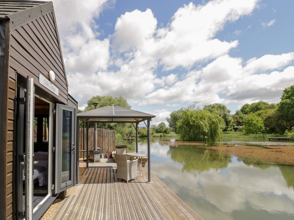 An outdoor area with a deck and chairs at Oak Lodge At Bridge Lake Farm & Fishery in Chacombe