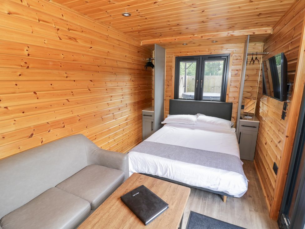 A bedroom with a bed and sofa at Oak Lodge At Bridge Lake Farm & Fishery Chacombe