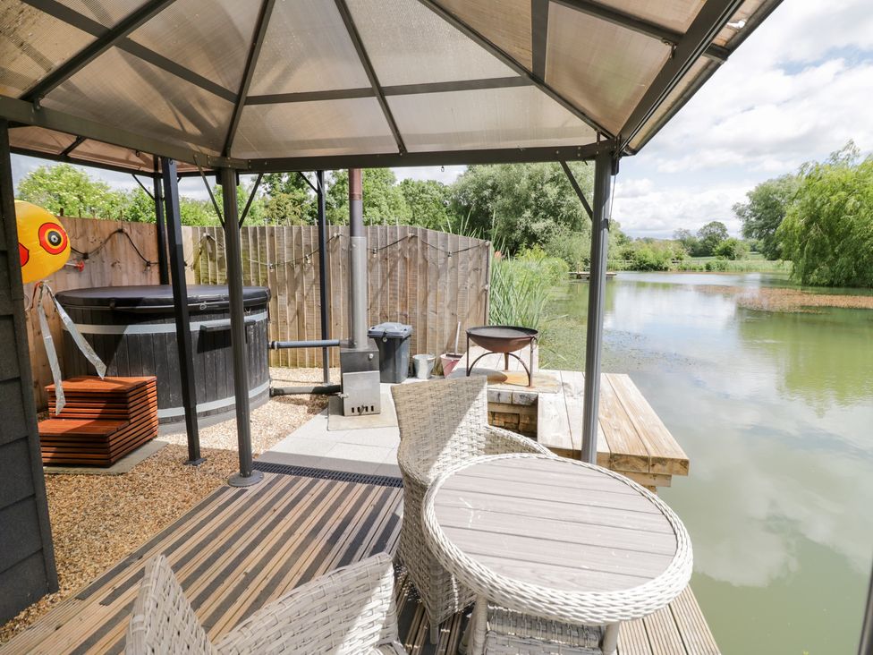 An outdoor area with a hot tub and seating at Oak Lodge At Bridge Lake Farm & Fishery Chacombe