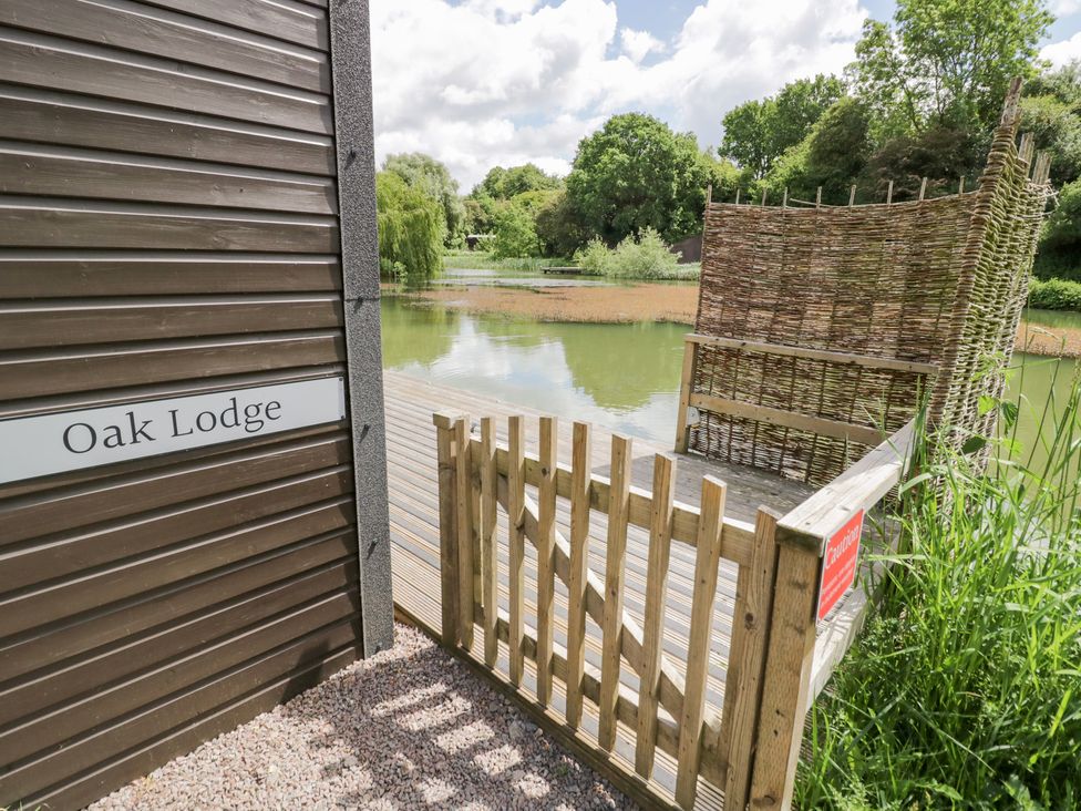 An outdoor area with gate and view of the lake at Oak Lodge At Bridge Lake Farm & Fishery Chacombe
