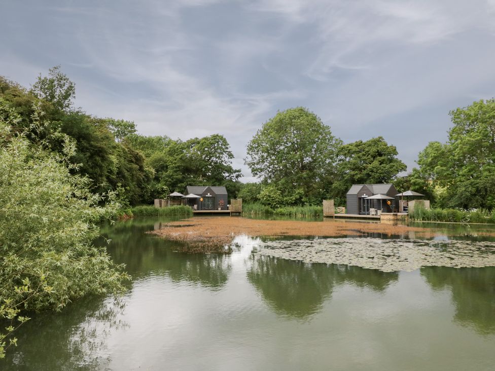 A view of houses by a pond at Oak Lodge At Bridge Lake Farm & Fishery Chacombe