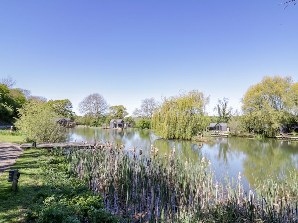 A pond with fishing huts at Oak Lodge At Bridge Lake Farm & Fishery in Chacombe