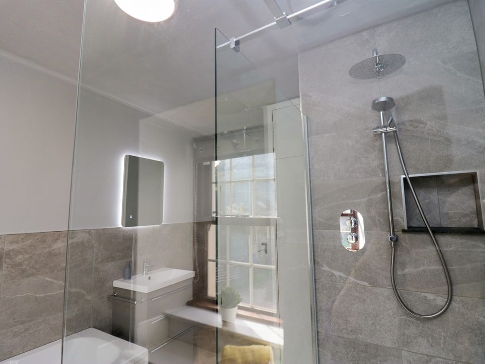 A bathroom with a shower, sink, and window at Beckside Farm Bootle near Millom Cumbria