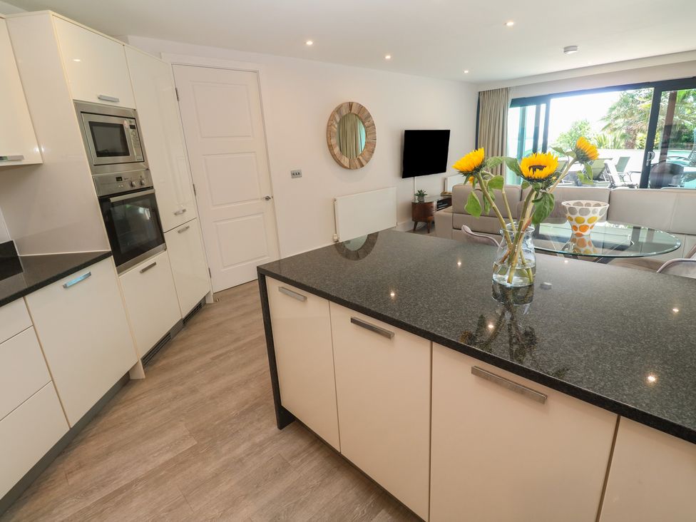 A kitchen with cabinets and a dining area at Peninsula Apartment 2 St Ives