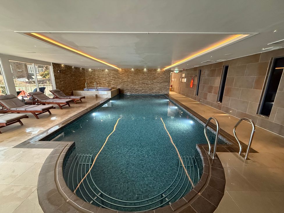 An indoor pool with deck chairs and a jacuzzi at Peninsula Apartment 2 St Ives