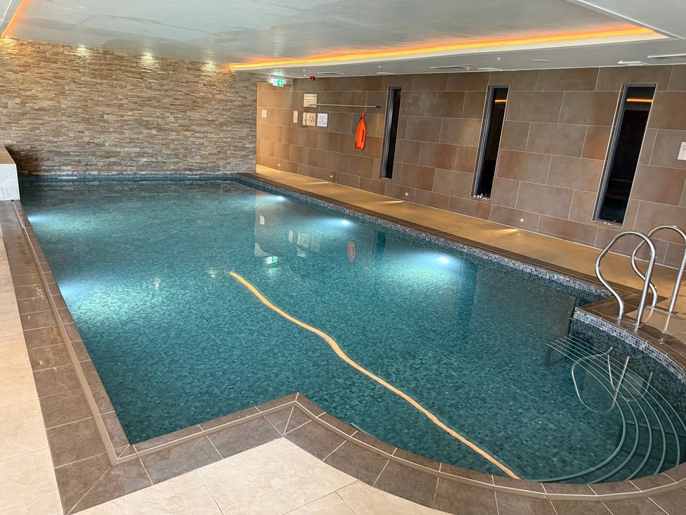 An indoor pool with a tiled wall and pool ladder at Peninsula Apartment 2 St Ives