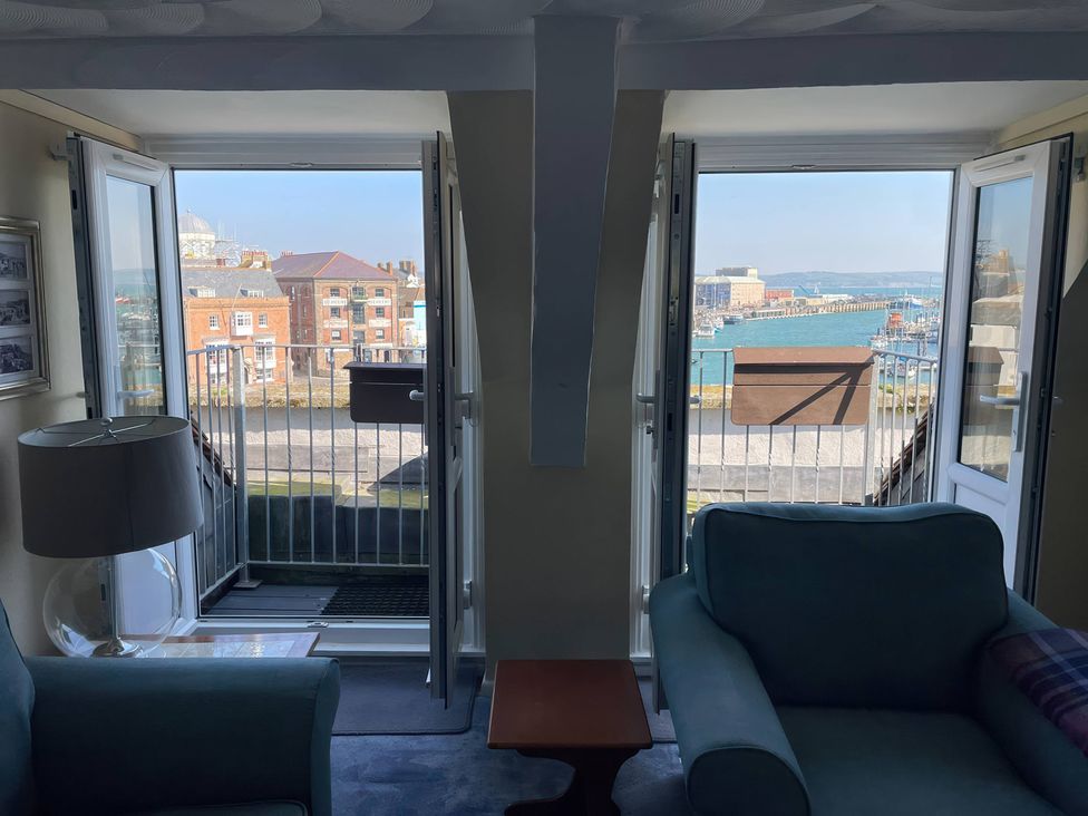 A living room with windows overlooking the harbor at Monarch in Brewers Quay Harbour