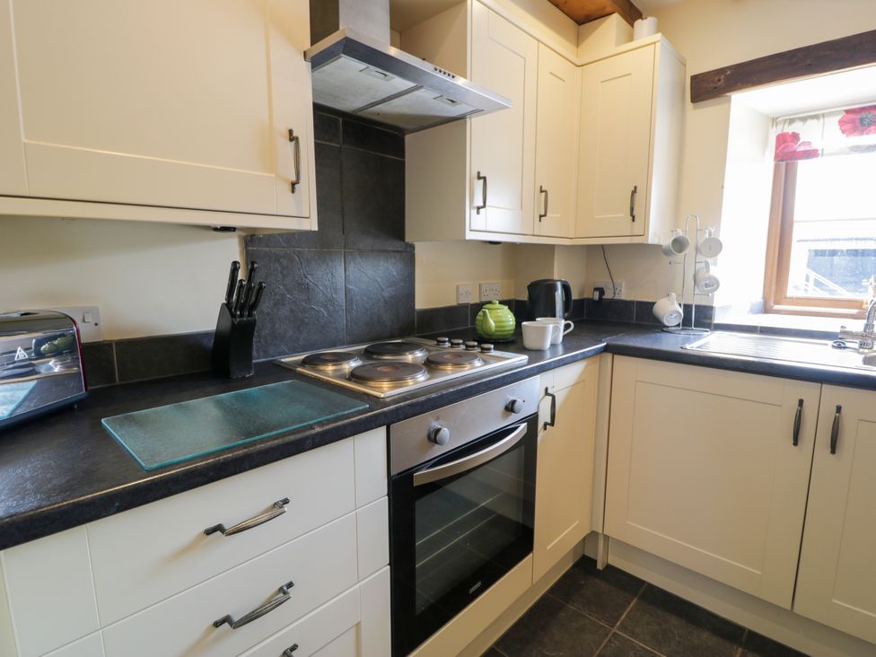 A kitchen with cabinets, countertop, sink and appliances at Bwthyn Y Wennol near Abergele