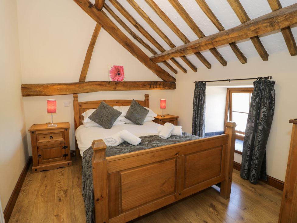 A bedroom with a wooden bed and bedside table at Bwthyn Y Wennol Dolwen near Abergele