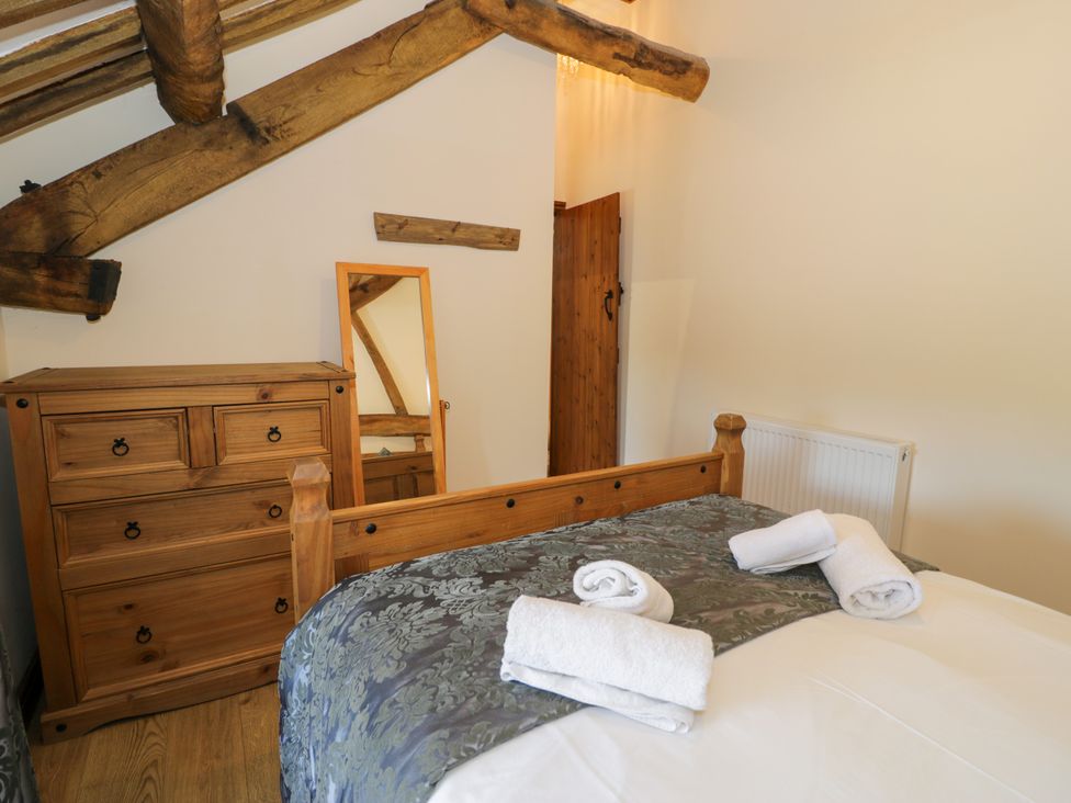 A bedroom with a bed and dresser at Bwthyn Y Wennol Dolwen near Abergele