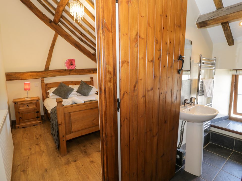 A bedroom with a bed and a bathroom area at Bwthyn Y Wennol Dolwen near Abergele