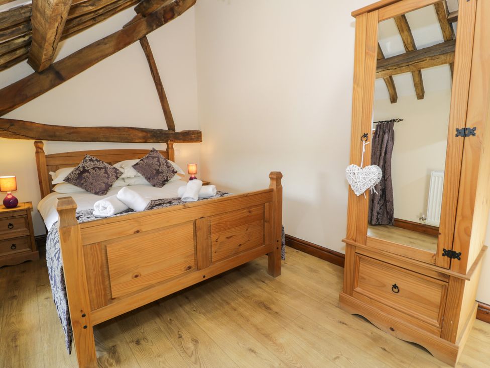 A bedroom with a wooden bed and mirror at Bwthyn Y Wennol Dolwen near Abergele